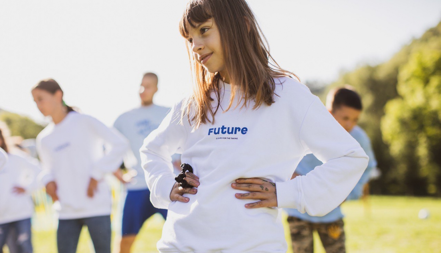 Bērni pļavā baltos džemperos ar uzrakstu Future